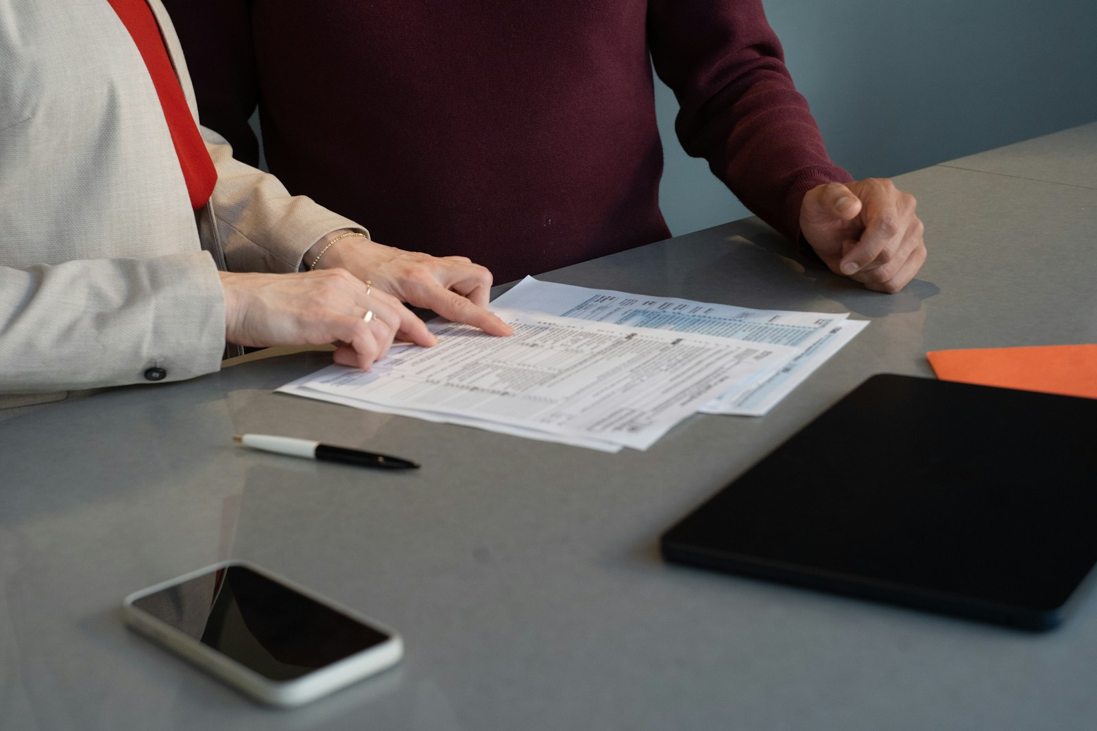 Two professionals reviewing printed documents together at a minimal office meeting table