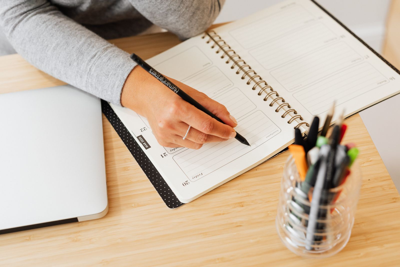 Hand writing weekly plans in a planner on a warm wooden desk
